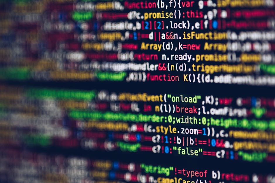 Close-up photograph of a computer screen displaying lines of computer code in various colors, including red, green, yellow, blue, and white, on a black background. The code consists of syntax highligh